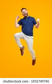 Full body of overjoyed young bearded male in casual outfit jumping with fists up and screaming while celebrating victory against bright yellow background - Shutterstock ID 1931749745