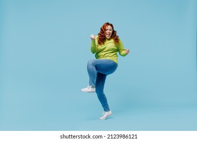 Full body overjoyed young chubby overweight plus size big fat fit woman wear green sweater do winner gesture raise up leg isolated on plain blue background studio portrait. People lifestyle concept - Shutterstock ID 2123986121