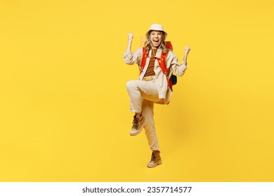 Full body overjoyed young woman carry bag with stuff mat do winner gesture isolated on plain yellow background. Tourist leads active lifestyle walk on spare time. Hiking trek rest travel trip concept - Shutterstock ID 2357714577