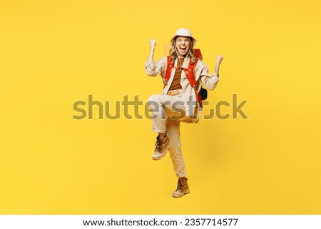 Full body overjoyed young woman carry bag with stuff mat do winner gesture isolated on plain yellow background. Tourist leads active lifestyle walk on spare time. Hiking trek rest travel trip concept