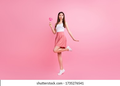 Full Body Photo Of Adorable Lady Send Air Kisses Hold Big Heart Shape Lollipop On Stick Good Mood Wear White Singlet Dotted Short Skirt Shoes Isolated Pastel Pink Color Background