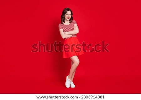 Full body photo of adorable youngster girl posing camera arms crossed wear cute crop top skirt sneakers isolated red color background