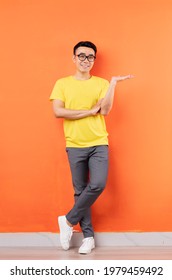 Full Body Photo Of Asian Man In Yellow Shirt On Orange Background

