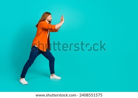 Full body photo of attractive blond hair guy hard working pushing copyspace invisible huge object isolated on aquamarine color background