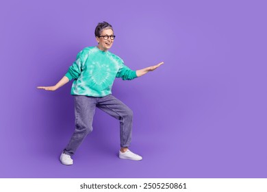 Full body photo of attractive senior woman surfing empty space dressed stylish green clothes isolated on purple color background - Powered by Shutterstock