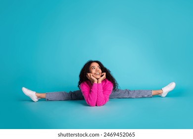 Full body photo of attractive teen girl sit split look empty space dressed stylish pink clothes isolated on aquamarine color background - Powered by Shutterstock