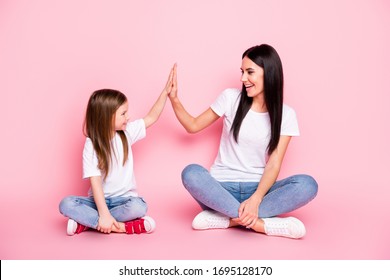 Full Body Photo Of Attractive Young Mom Small Daughter Best Friends Sit Floor Crossed Legs Clap Arms Cool Team Wear Casual White T-shirts Jeans Shoes Isolated Pastel Pink Color Background