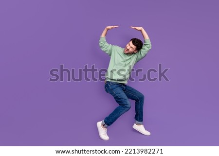 Full body photo of attractive young man lifting heavy falling ceiling dressed stylish khaki garment isolated on purple color background