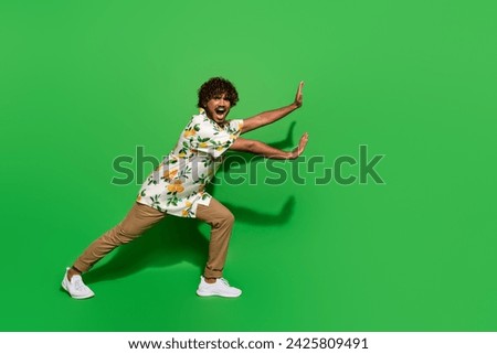 Full body photo of attractive young man push empty space promo wear trendy citrus print clothes isolated on green color background