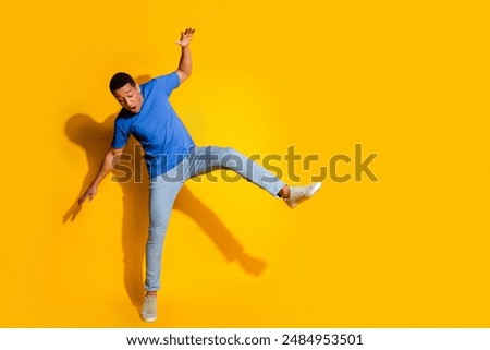 Full body photo of attractive young man falling look down empty space dressed stylish blue clothes isolated on yellow color background