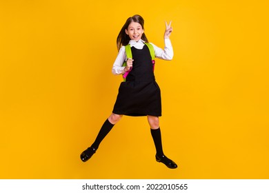 Full body photo of brown haired young small girl jump up make v-sign wear bag isolated on yellow color background