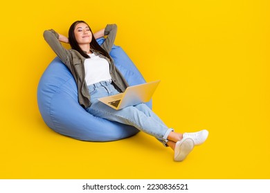 Full body photo brunette hair vietnamese entrepreneur it manager lying down pouf nap sleep with laptop after work isolated on yellow color background