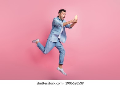 Full Body Photo Of Brunette Man Hold Phone Amazed News Run Jump Wear Casual Outfit Isolated On Pink Color Background