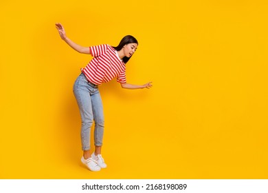 Full body photo of charming young girl standing tip toe look empty space abyss isolated on yellow color background - Shutterstock ID 2168198089