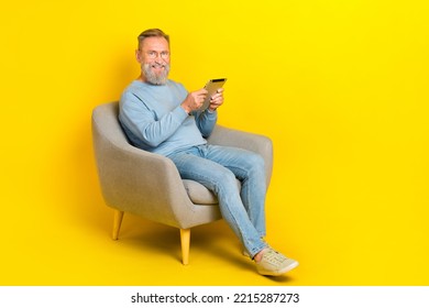 Full Body Photo Of Cheerful Aged Man Sit Chair Hold Use Tablet Isolated On Yellow Color Background