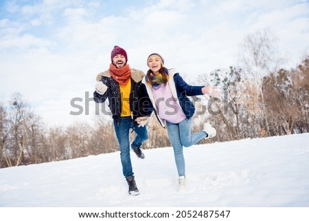 Full body photo of cheerful couple happy positive smile walk park winter snowy have fun hold hands together enjoy