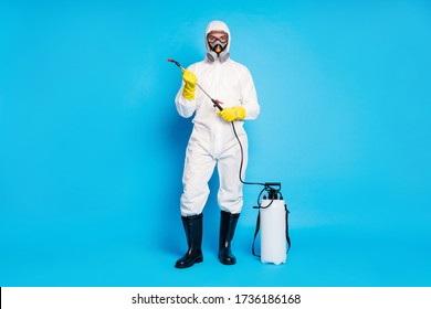 Full Body Photo Of Confident Medical Worker Man Hold Spray Equipment Ready Protect People Ncov Infection Epidemic Wear Biological Suit Uniform Boots Isolated Blue Color Background