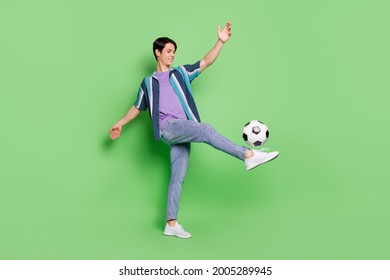 Full body photo of cool brunet millennial guy play football wear shirt jeans isolated on green color background