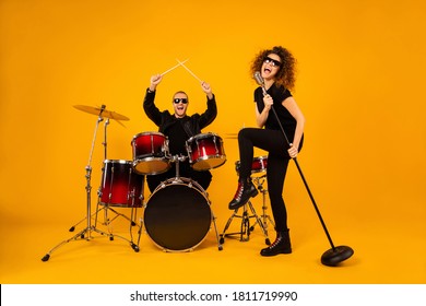 Full Body Photo Of Cool Rock Group Handsome Guy Play Drum Instruments Crazy Girl Sing Old Fashion Mic Concert Popular Band Wear Trendy Rocker Leather Outfit Isolated Yellow Background