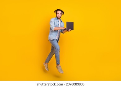 Full body photo of cool young guy jump type laptop wear jeans shirt footwear isolated on yellow color background - Shutterstock ID 2098083835