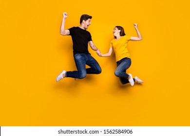 Full body photo of crazy guy lady couple jump high raise fists celebrate first place football league favorite team wear casual jeans t-shirts isolated yellow color background - Shutterstock ID 1562584906