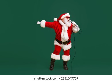 Full body photo of crazy santa claus sing microphone song on christmas x-mas newyear disco wear sunglass headwear cap isolated over bright shine color background - Powered by Shutterstock