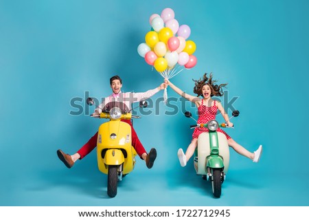 Full body photo of crazy two people lady guy drive retro moped travelers spread legs raise arms many air balloons birthday guests rejoicing vintage clothes isolated blue color background
