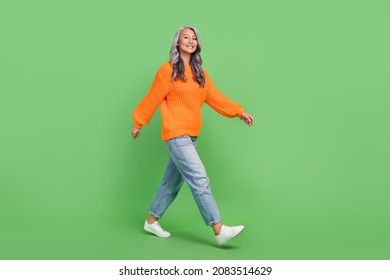 Full body photo of cute grey hair aged lady go wear pullover jeans sneakers isolated on green color background