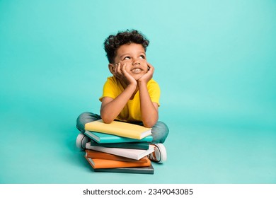 Full body photo of cute little boy look empty space lean on books pile wear trendy yellow clothes isolated on aquamarine color background - Powered by Shutterstock