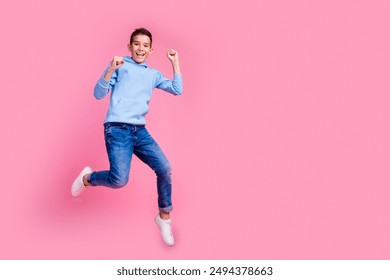 Full body photo of cute teen boy jumping winning dressed stylish blue clothes isolated on pink color background - Powered by Shutterstock