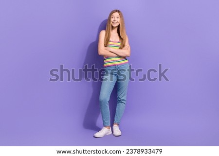 Full body photo of cute teen blonde woman folded hands look empty space wear trendy striped clothes isolated on purple color background