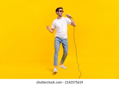 Full body photo of cute young brunet guy sing wear eyewear t-shirt jeans footwear isolated on yellow background - Shutterstock ID 2142575619