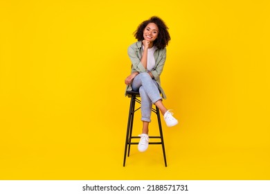 Full body photo of cute young girl wavy hair sit stool smiling banner dressed stylish khaki clothes isolated on yellow color background - Shutterstock ID 2188571731
