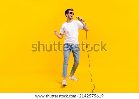 Full body photo of cute young brunet guy sing wear eyewear t-shirt jeans footwear isolated on yellow background