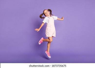Full body photo of dreamy positive little girl jump up air wear pink shoes isolated on purple color background - Shutterstock ID 1873735675