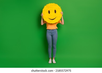 Full Body Photo Of Excited Carefree Person Hands Hold Large Smile Emoji Cover Face Isolated On Green Color Background