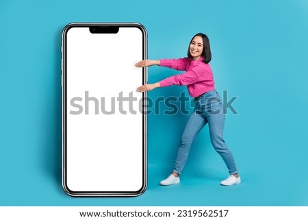 Full body photo of excited filipino lady hands pull huge empty space smart phone isolated on blue color background