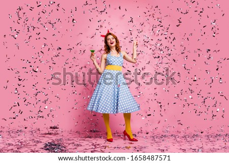 Full body photo of funky lady hold green cocktail theme retro party dancing star confetti falling wear headband dotted dress yellow tights red high-heels isolated pink color background