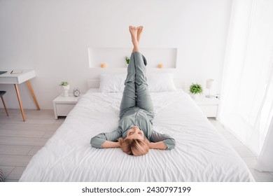 Full body photo of funky positive girl blonde hair lying on bed head over heel chill enjoying rest time at home during weekend indoors - Powered by Shutterstock