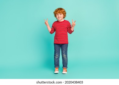 Full Body Photo Of Funky Small Boy Show V-sign Wear Shirt Jeans Sneakers Isolated On Blue Background