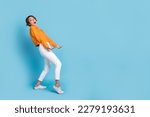 Full body photo of funky young woman carry heavy invisible box empty space dressed stylish orange look isolated on blue color background