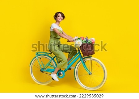 Full body photo of gorgeous young lady riding bicycle feminine movement wear trendy khaki clothes isolated on yellow color background