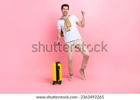 Full body photo of guy fist up hooray celebrate his victory free pass tickets traveler carry suitcase isolated on pink color background