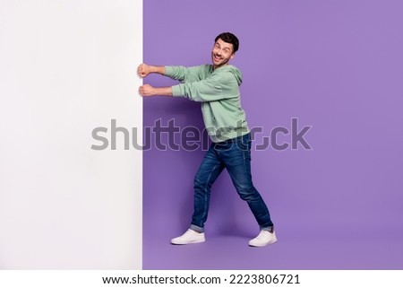 Full body photo of handsome young man pulling white empty space placard wear trendy gray look isolated on violet color background