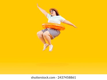 Full body photo of a happy funny fat plus size woman in sunglasses with rubber ring jumping and having fun on studio yellow background. Funny overweight tourist is going on summer holiday trip. - Powered by Shutterstock