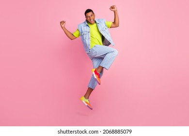 Full Body Photo Of Impressed Millennial Guy Jump Yell Wear Vest T-shirt Jeans Sneakers Isolated On Pink Background