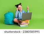 Full body photo of intelligent little girl wear blue pullover sit with laptop directing empty space isolated on green color background