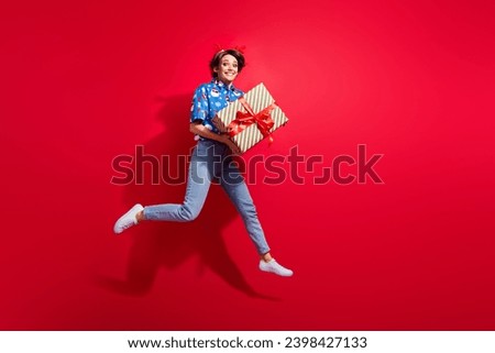Full body photo of jumping careless crazy girl bring surprise box wrapped package happy winter holidays isolated on red color background