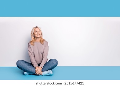 Full body photo of lovely senior lady sit floor crossed legs empty space dressed stylish gray garment isolated on blue color background - Powered by Shutterstock