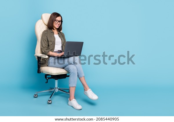 Full body photo of manager ceo lady sit chair\
use device netbook online communicate wear jeans isolated over blue\
color background
